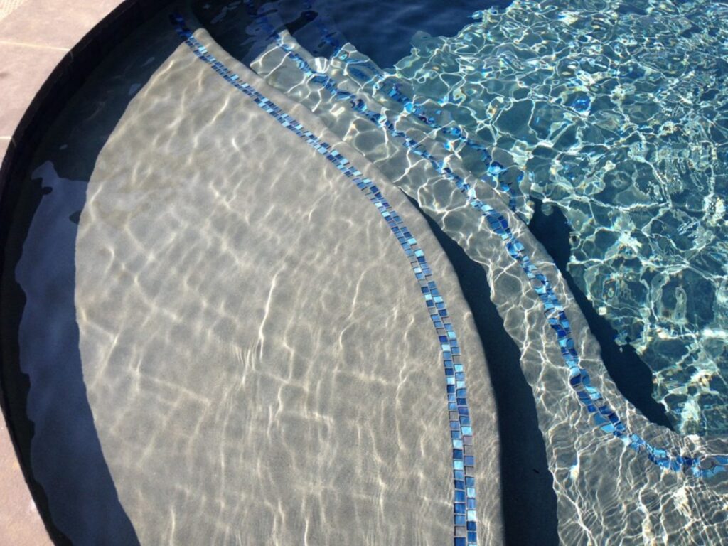 A crystal clear pool with aqua and blue tile steps.
